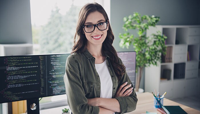 Adobe image of woman in front of desktop computer with coding